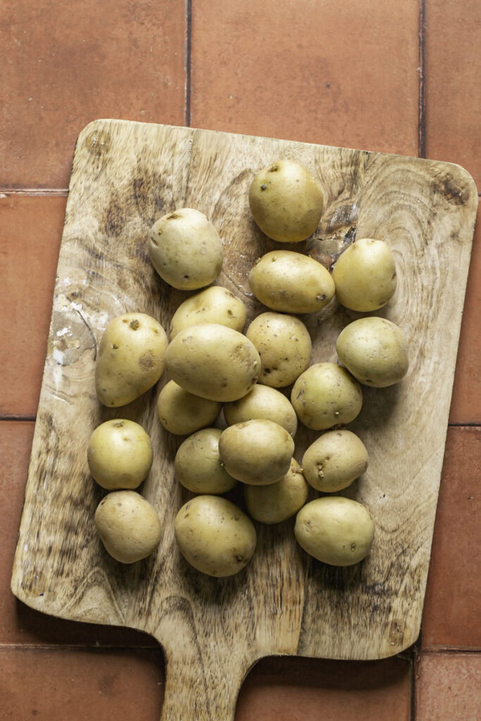 whole petit gold potatoes on a wooden cutting board.