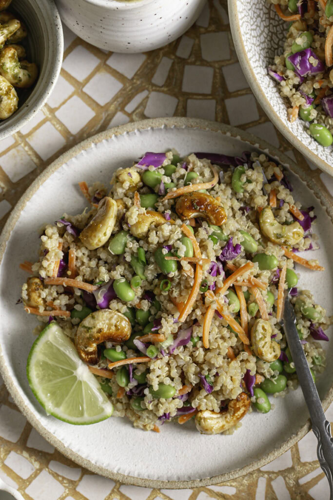 close up overhead shot of edamame quinoa salad on a plate with a lime slice.