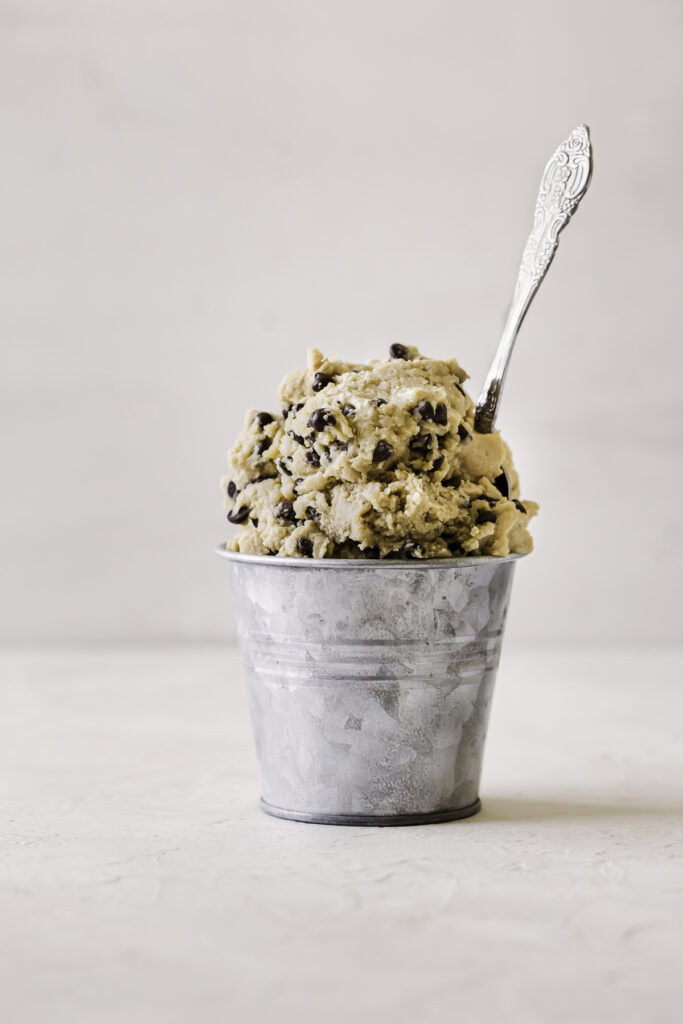 raw almond flour cookie dough in a small metal bucket with a spoon sticking out of it.