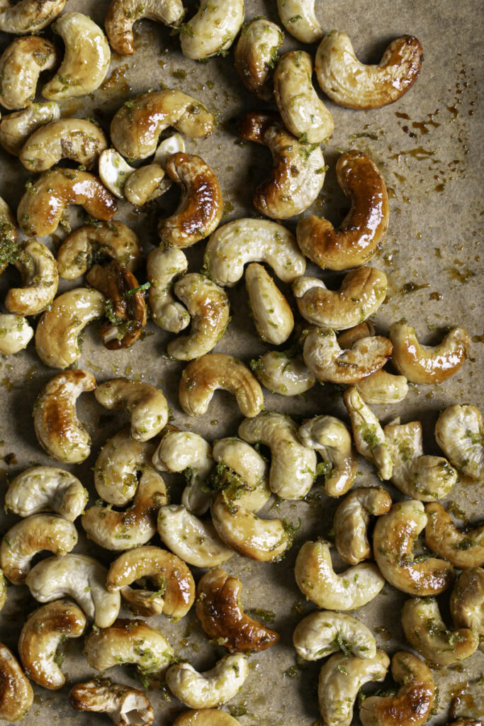 agave lime roasted cashews on a parchment lined baking sheet.