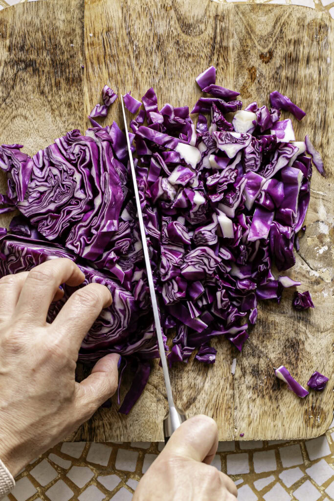 action shot of chopping the slices of red cabbage with a knife. 