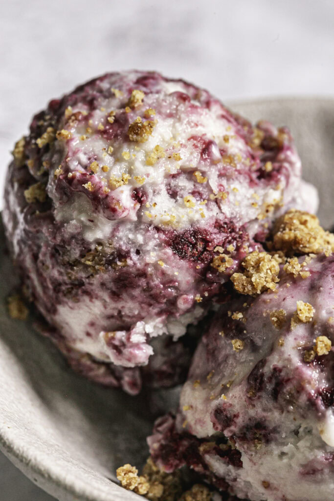 a close up macro shot of a scoop of blackberry cobbler ice cream.