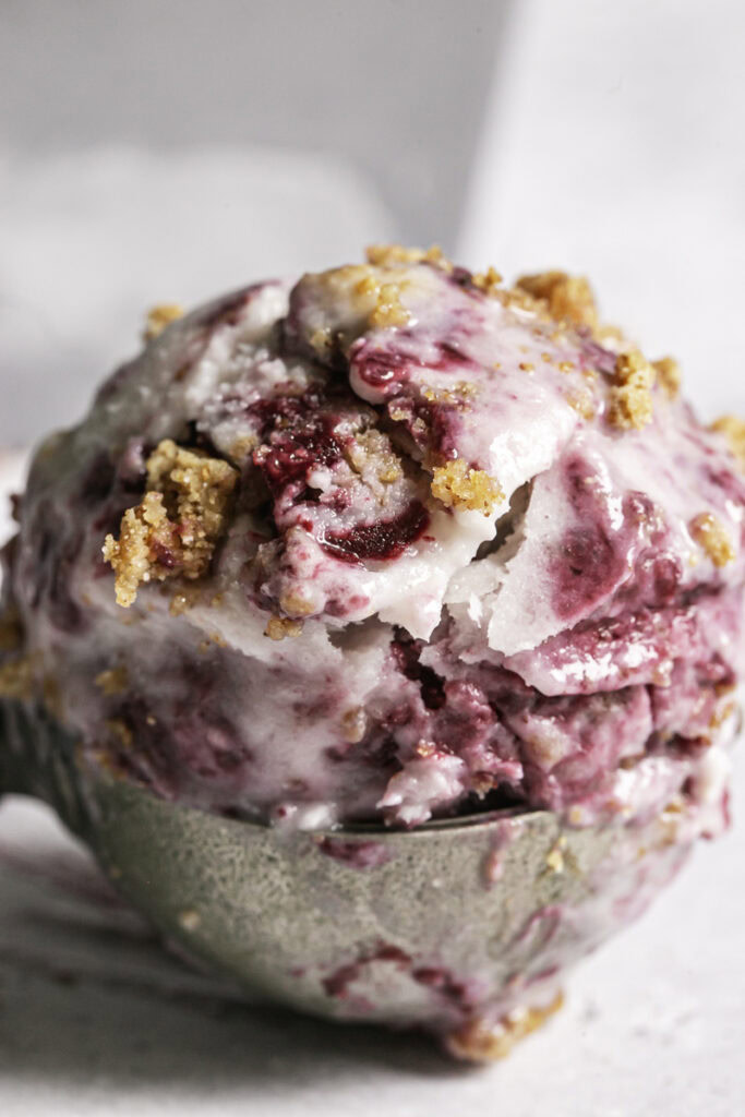 close up of a scoop of blackberry cobbler ice cream in an ice cream scoop.