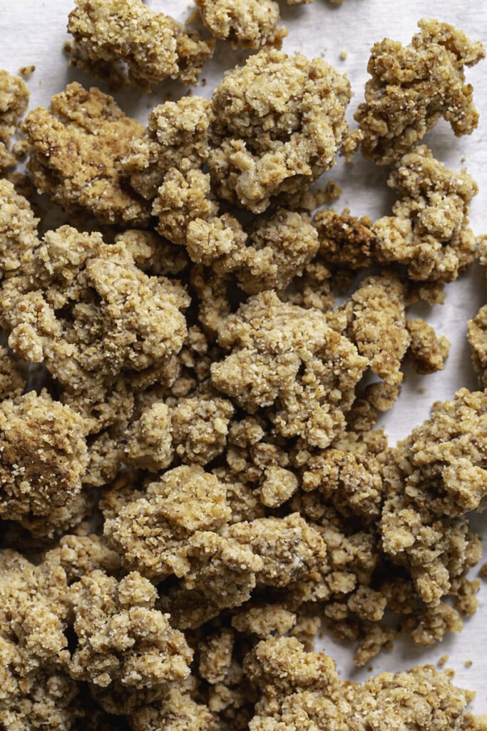 a close up of almond flour biscuit crumble on a piece of parchment paper.