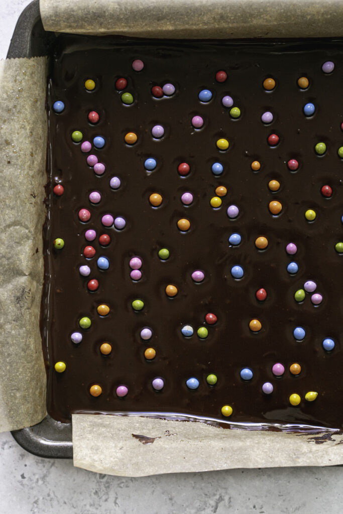 overhead close up of rainbow sprinkles on the chocolate ganache topping.