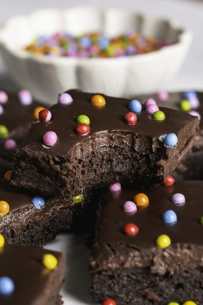 a close up of cosmic brownies, one stacked on top of the others with a bite taken out of it.