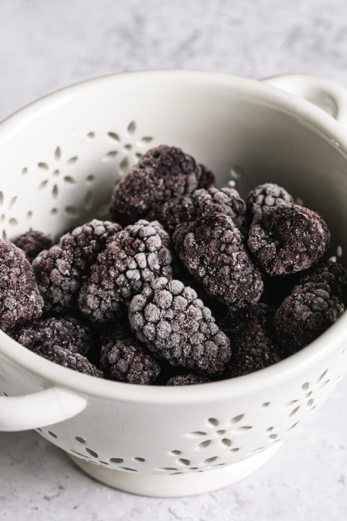 frozen blackberries in a small berry strainer.