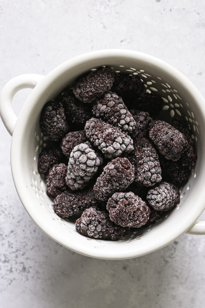 frozen blackberries in a small berry strainer.