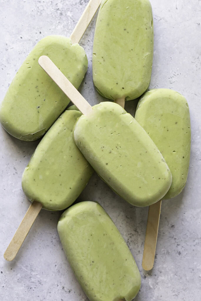 creamy avocado mint chocolate ice cream bars stacked on top of one another, the top one not yet coated in chocolate.