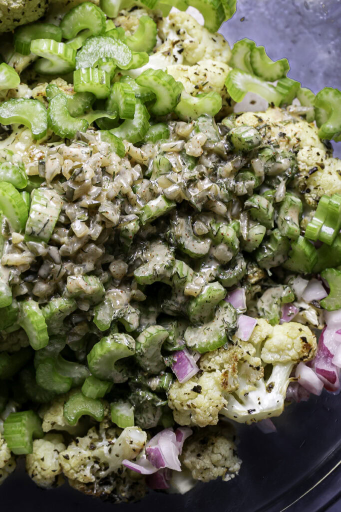 all of the ingredients for Low Carb Roasted Cauliflower Potato Salad in a large glass bowl before being tossed together.
