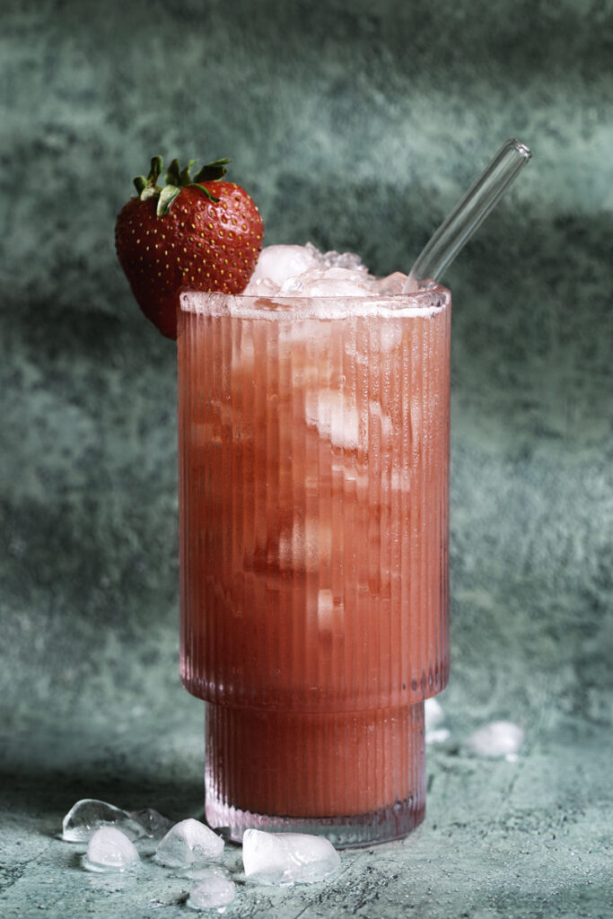 a large glass of watermelon strawberry water poured over ice.