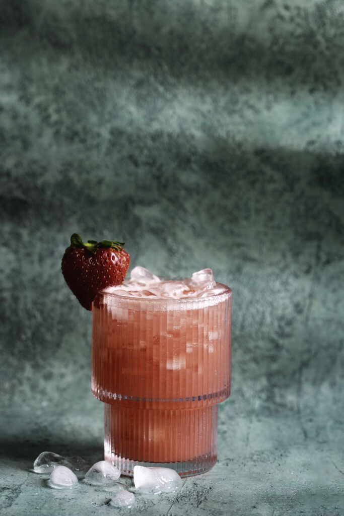 a small glass of watermelon strawberry water poured over ice.