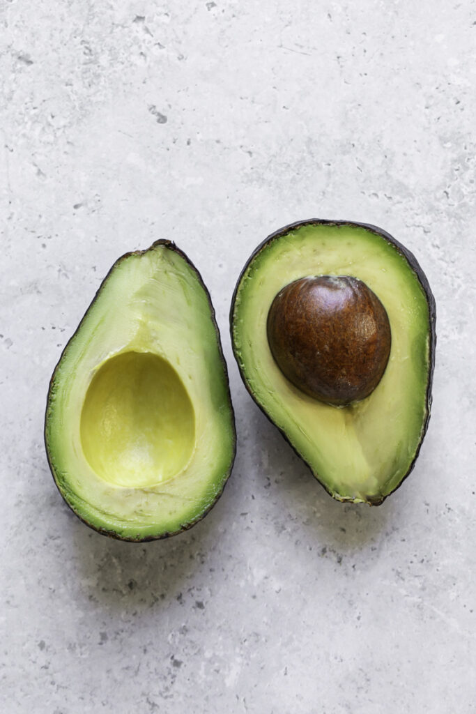 an avocado sliced in half with the pit in one side.