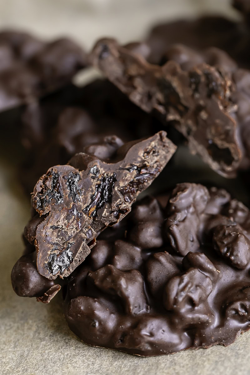 close up of chocolate raisin clusters, one cut in half sitting on another cluster.