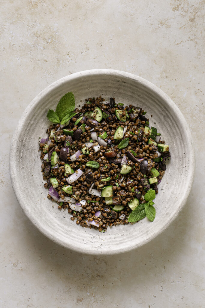 a bowl of roasted lentil greek salad in a large bowl.