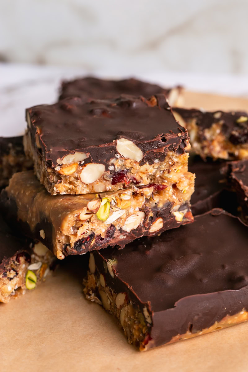 sliced trail mix bars stacked on top of each other on a piece of parchment paper.