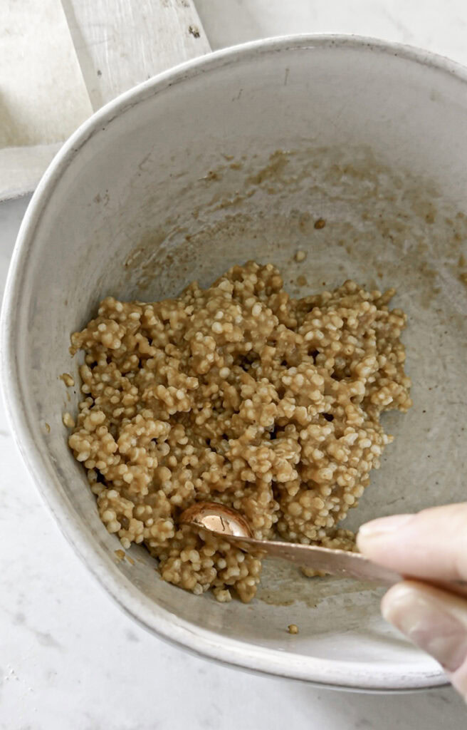 scooping the quinoa cookie mixture with a measuring spoon.