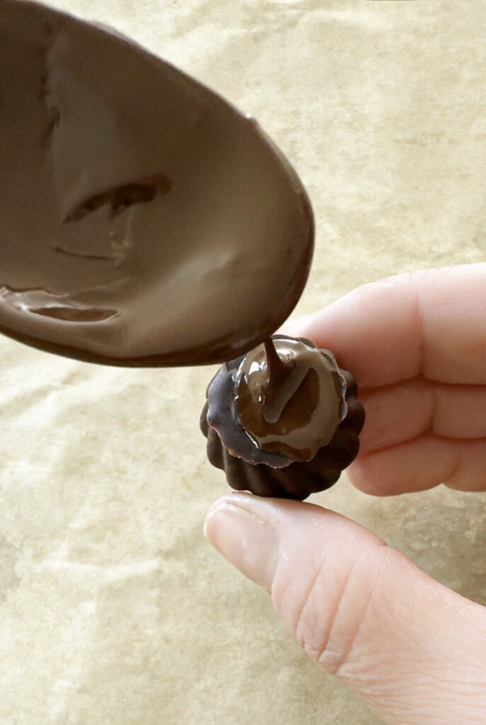spreading melted chocolate on the flat side of the chocolate kiss.