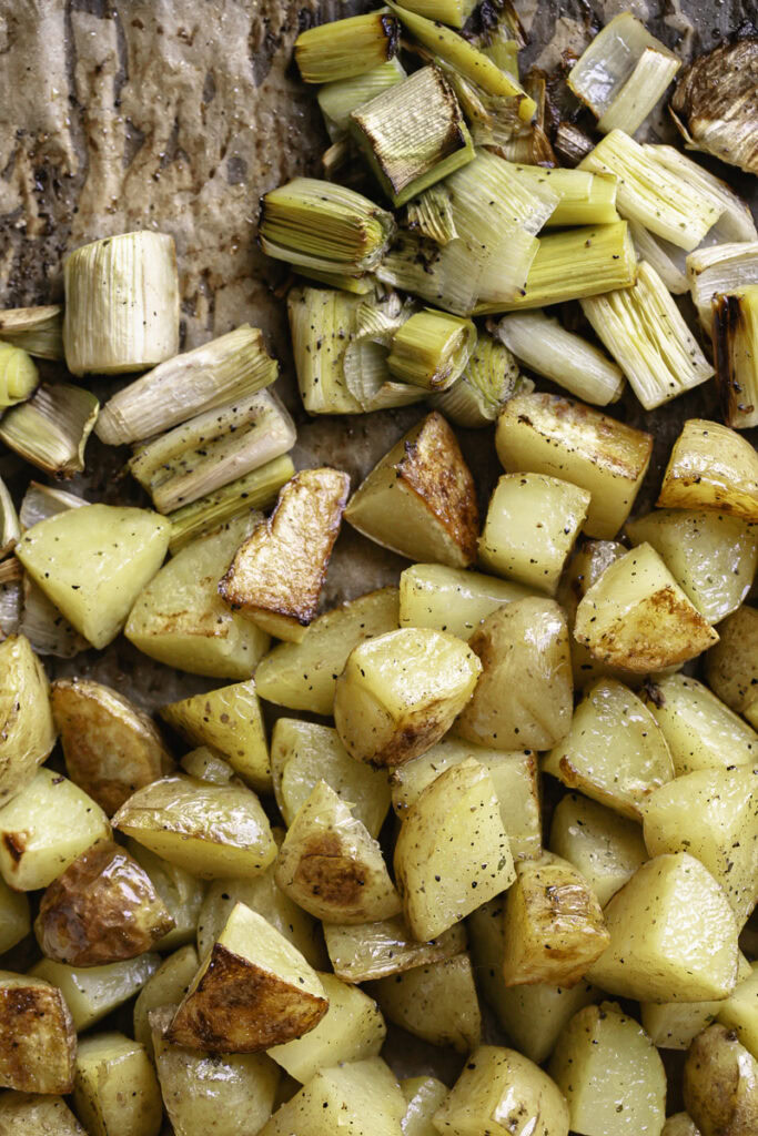 roasted gold potatoes and leeks on a parchment-lined baking sheet.