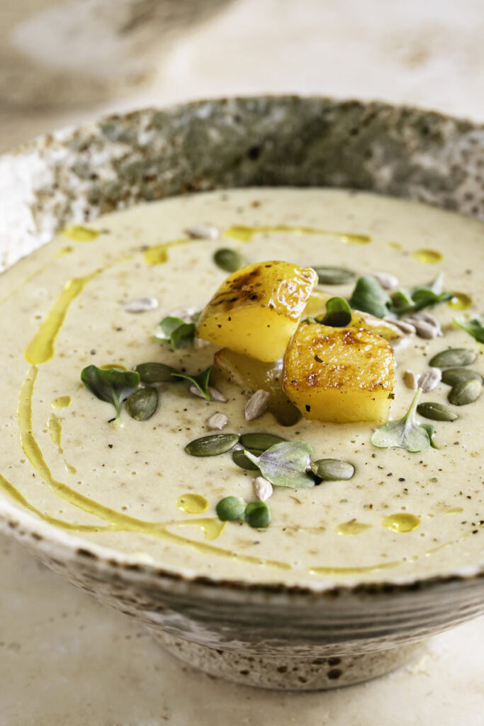 close up 3/4 shot of a bowl of Creamy Roasted Gold Potato Leek Soup.