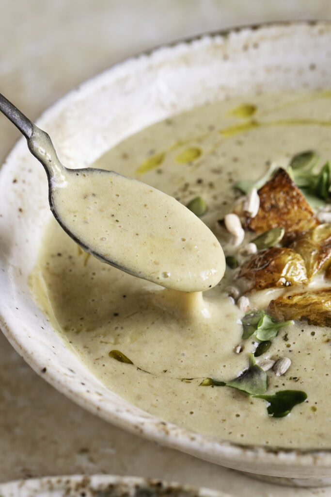 close up action shot of a spoon scooping some soup out of the bowl.