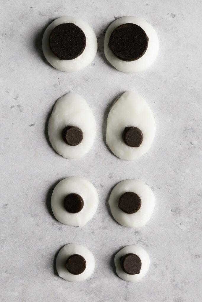 four different shapes and sizes of chocolate candy googly eyes lined up in a row.
