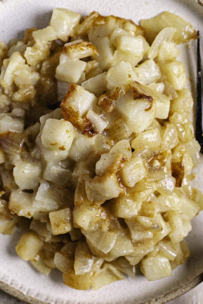close up overhead shot of creamy vegan hashbrown potato casserole on a plate.