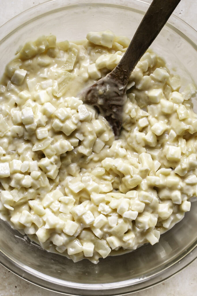 frozen hashbrown potatoes stirred into the roux in a glass bowl.