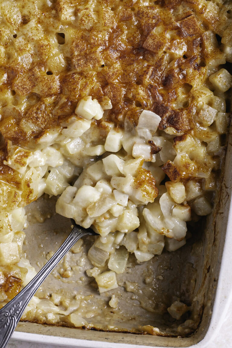 overhead shot of creamy vegan hashbrown casserole in a baking dish with a serving spoon in the casserole dish.
