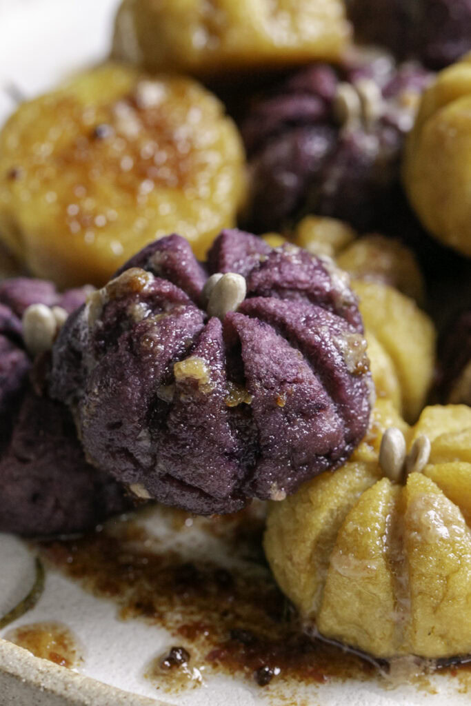 Close up of a baked purple pumpkin shaped mashed potato bite.