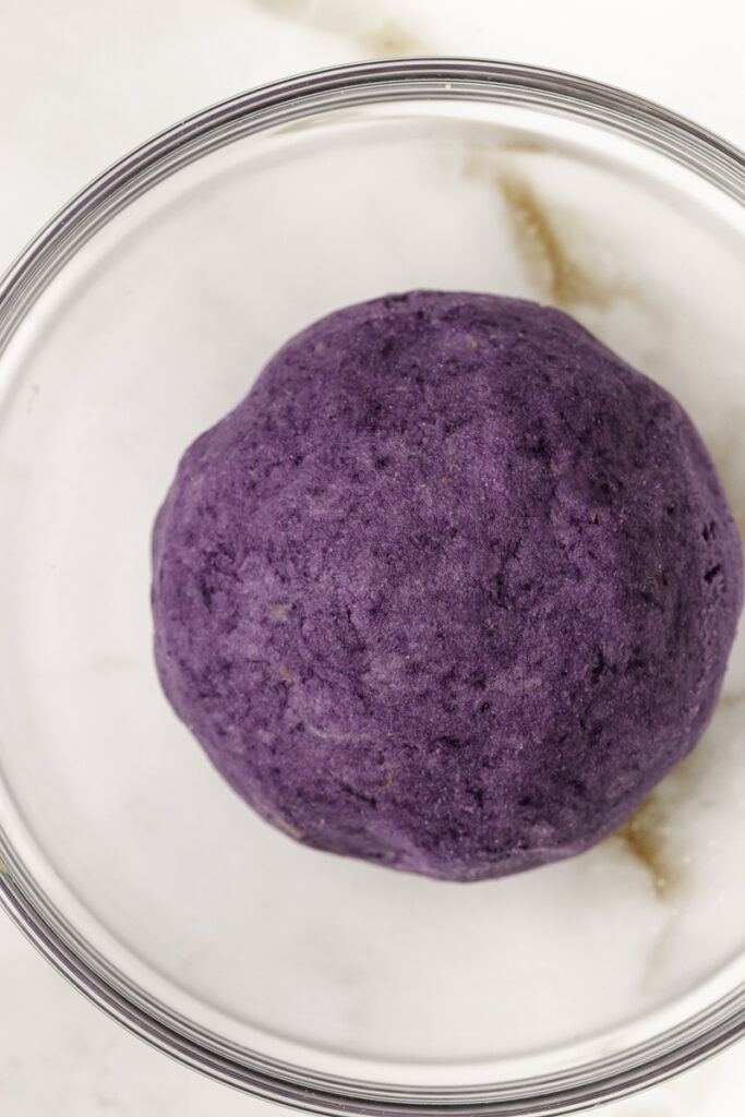 purple mashed potato dough rolled into a ball in a glass bowl.