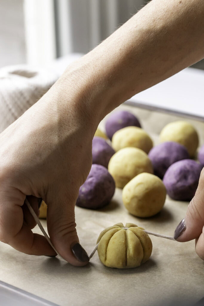 action shot of hands scoring a mashed potato ball into a pumpkin shape with a piece of cooking twine.
