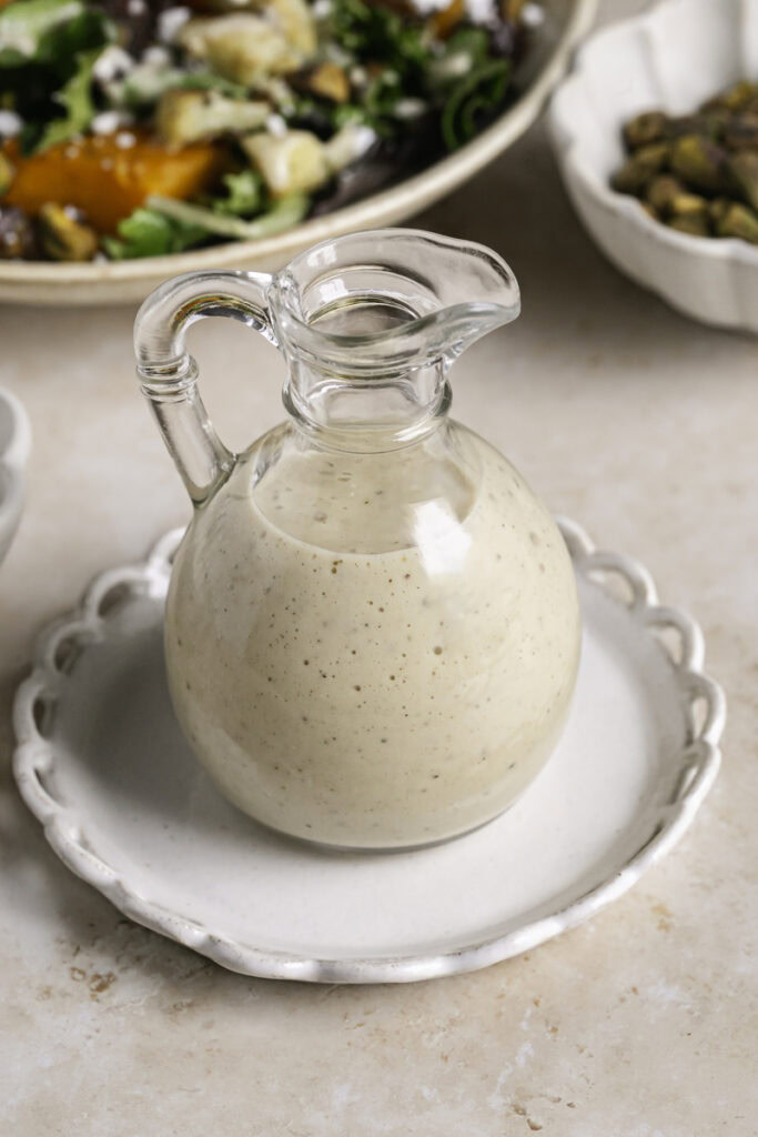 a jar of creamy apple cider vinaigrette dressing on a plate.