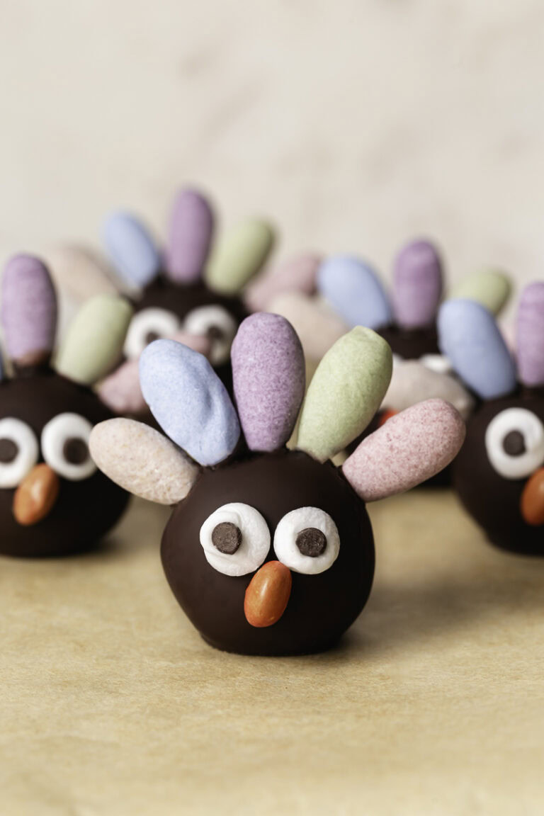 no-bake date almond flour brownie bite turkeys with pastel colored almond feathers, googly eyes and a candy beak.