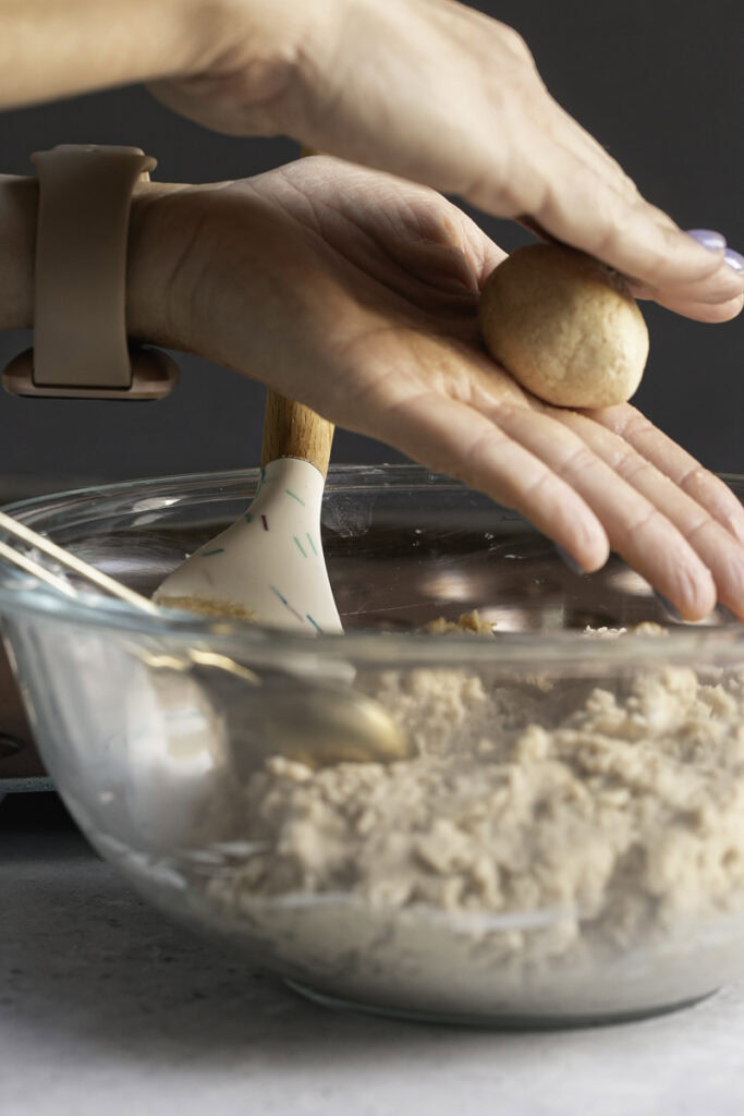 action shot rolling donut holes in hands.