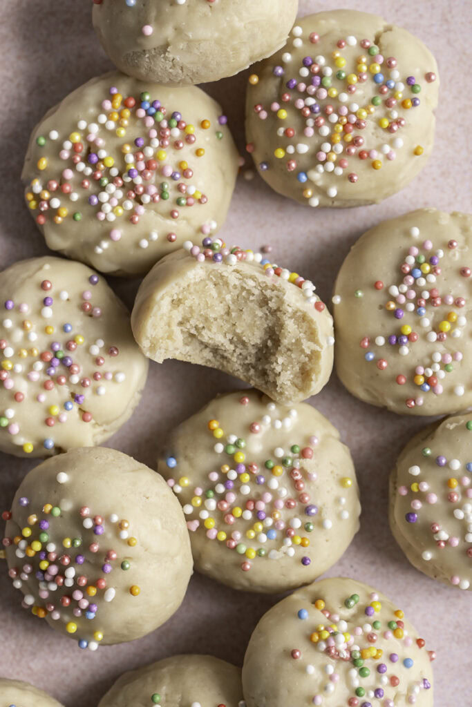 overhead shot of Buttery Soft Italian Sprinkle Biscotti Cookies, the middle one with a bite taken out of it to reveal the cookie texture.