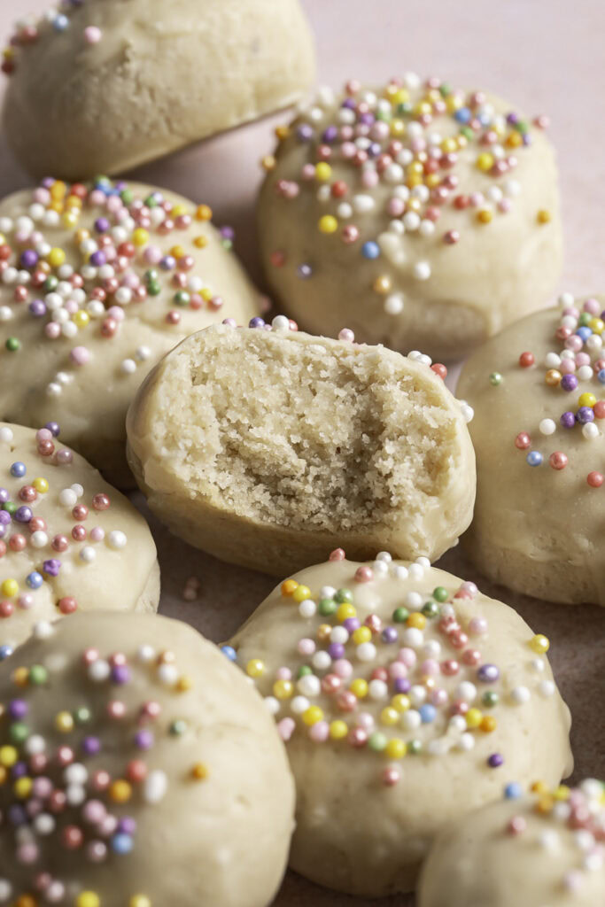 close up overhead shot of Buttery Soft Italian Sprinkle Biscotti Cookies, the middle one with a bite taken out of it to reveal the cookie texture.