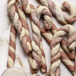 shortbread candy cane cookies piled on top of each other next to a glass of oat milk.