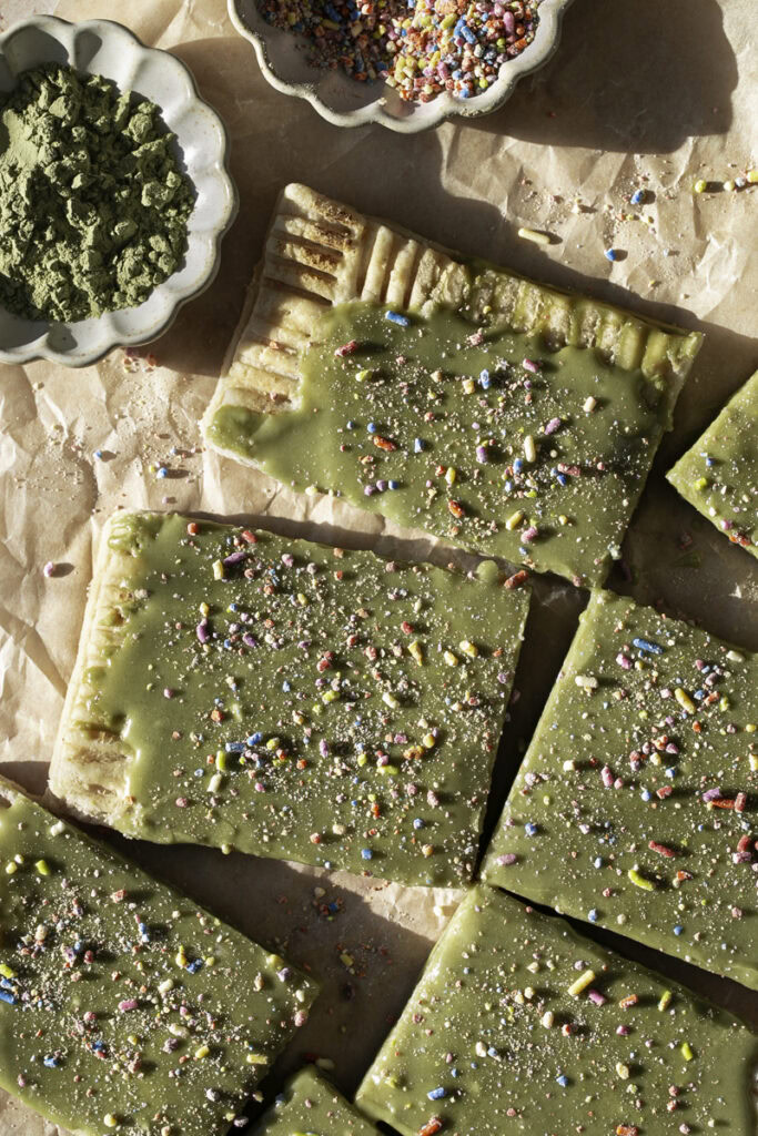 close up of cut slices of a giant frosted matcha pop tart decorated with sprinkles.