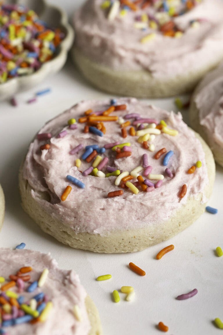 3/4 shot of soft frosted and sprinkled sugar cookies and a bowl of sprinkles.