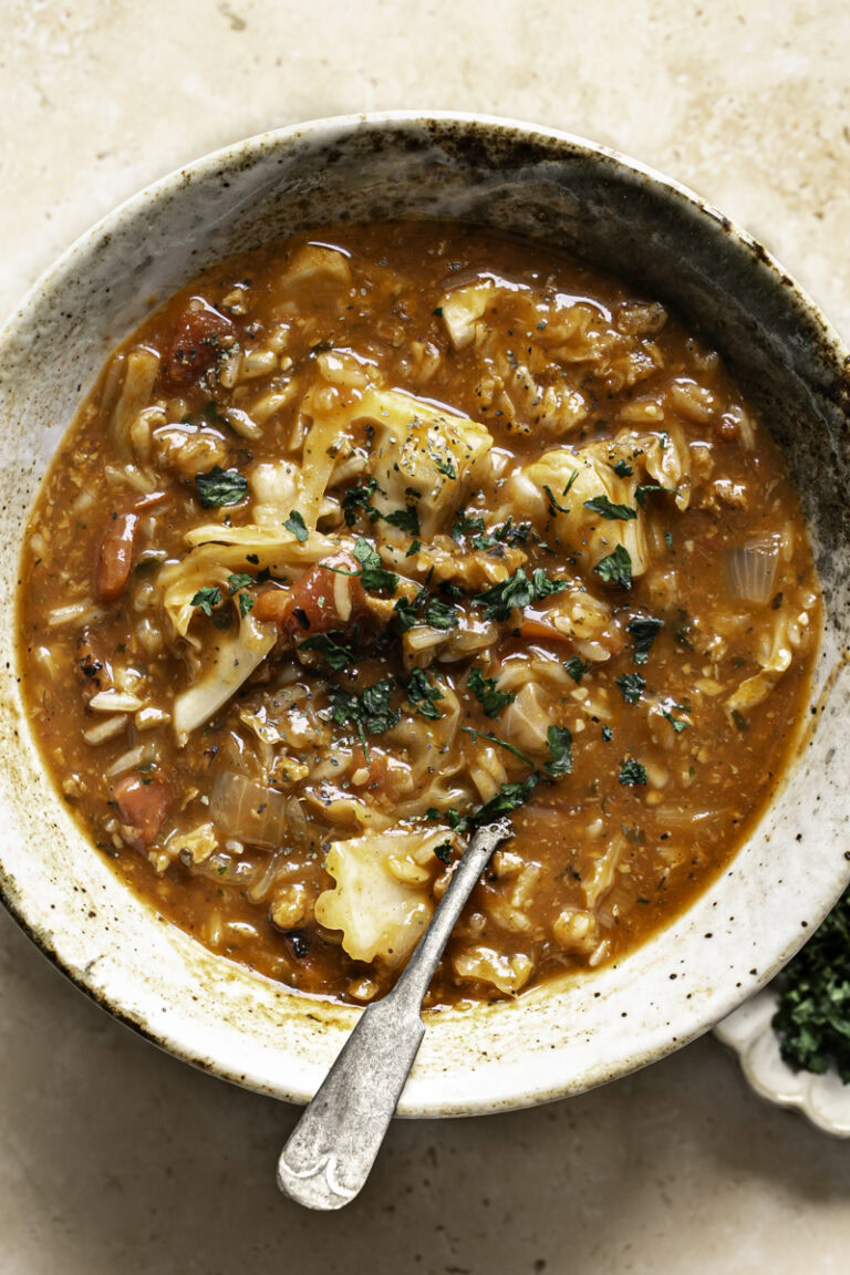 a bowl of vegan cabbage roll soup with a spoon in it.