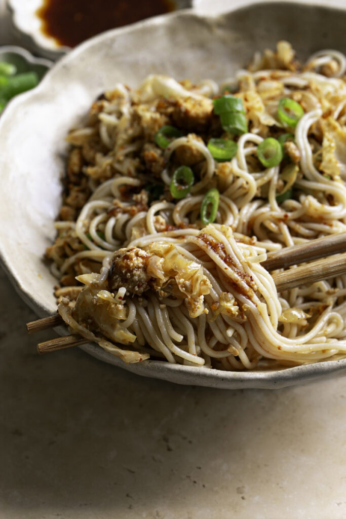 close up of Red Curry Tofu Cabbage Ramen Noodles with noodles twirled around chopsticks.
