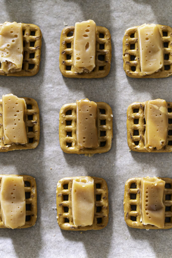 unwrapped caramels on top of pretzel squares.
