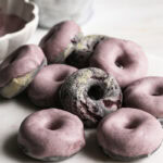 mini baked black berry cake donuts with blackberry frosting on a marble plate with