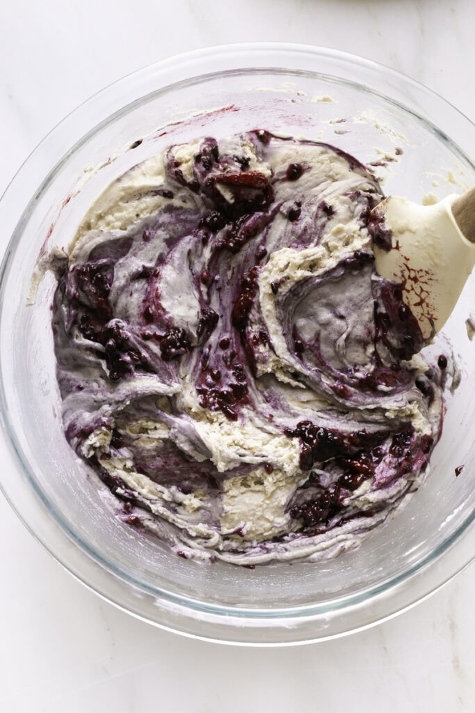 Mini Baked Blackberry Cake Donut cake batter in a glass bowl with a spatula.
