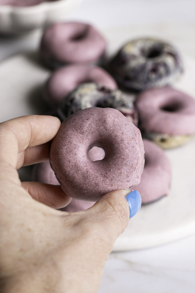 hand holding a mini baked blackberry cake donut.