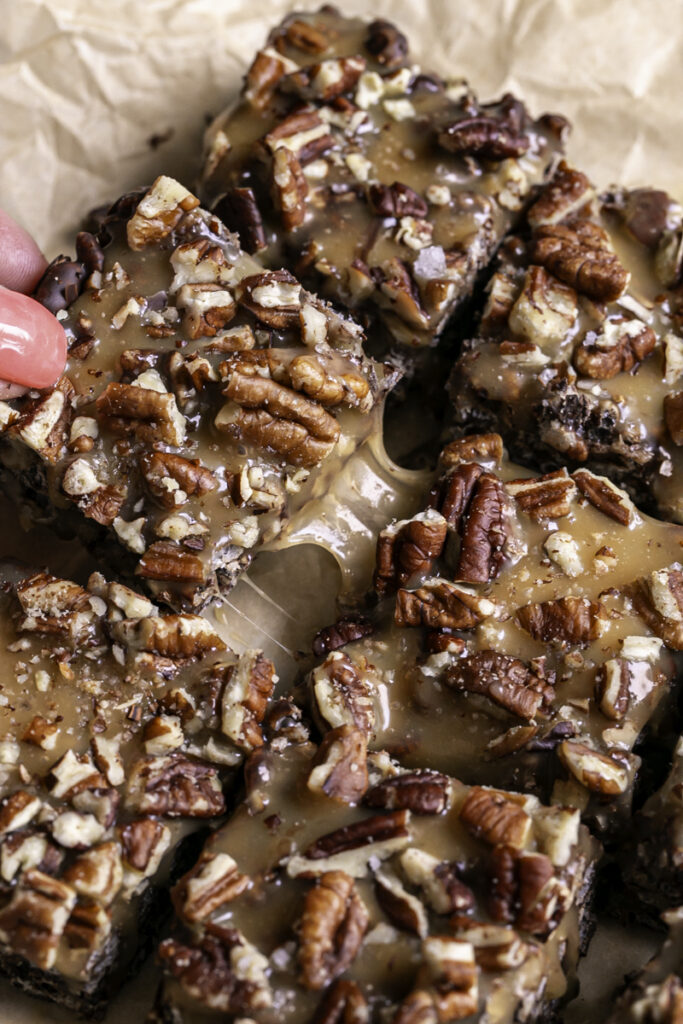 pulling apart turtle crispy rice squares to reveal the gooey caramel.