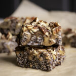 two turtle crispy rice squares stacked on top of one another on a piece of parchment paper.