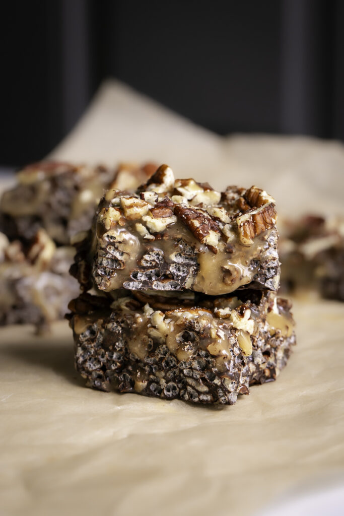 two turtle crispy rice squares stacked on top of one another on a piece of parchment paper.