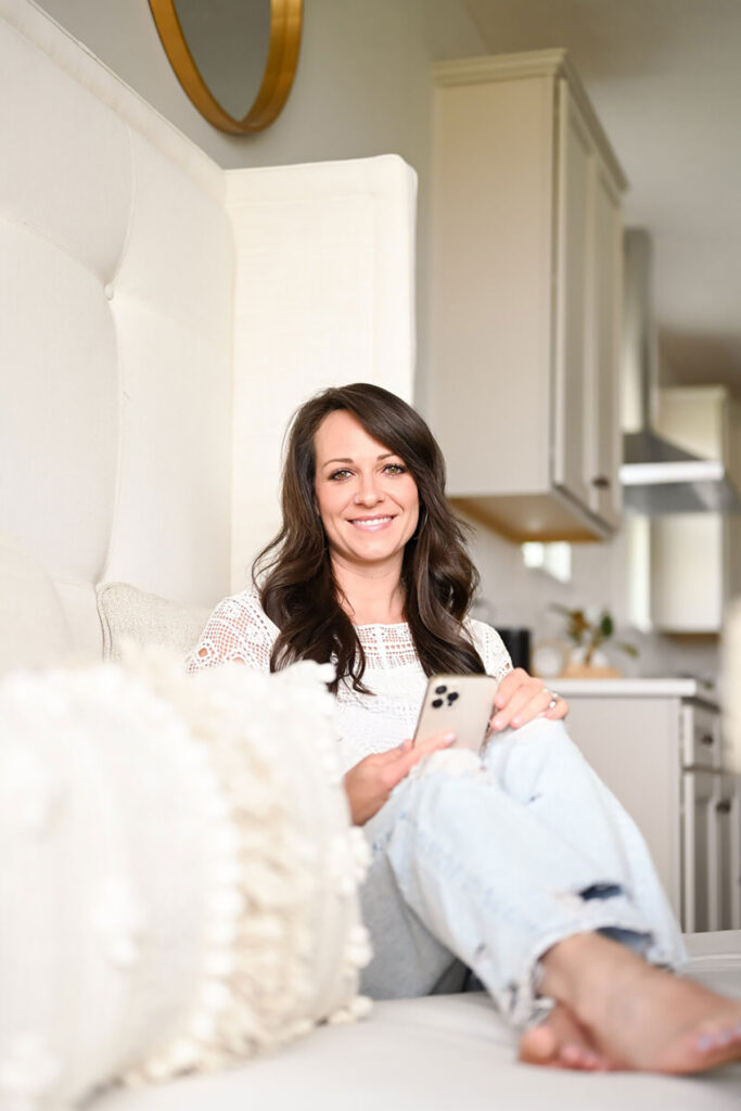 Gina sitting on the couch holding her phone
